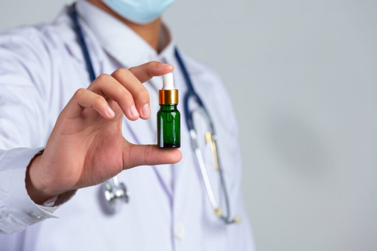 close up picture medical doctor holding bottle cannabis oil white wall